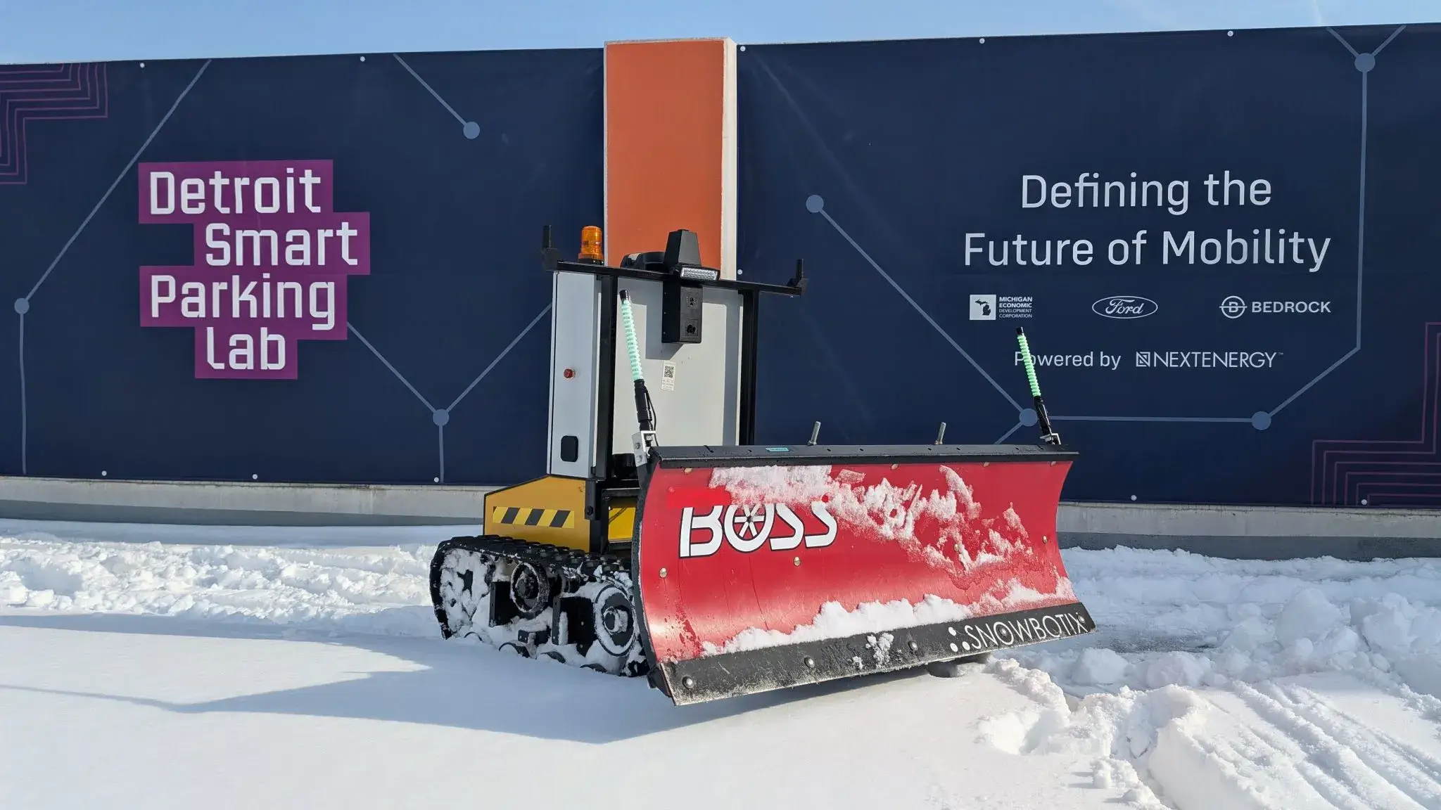 A Snowbotix SMUR unit with a front plow blade clearing snow on the Detroit Smart Parking Lab deck.