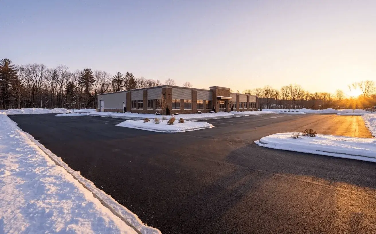 A cleared commercial car park at sunrise with snow banked at the edges, ready for opening.